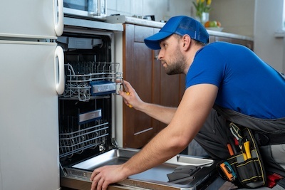 Repair of dishwashers. Repairman repairing dishwasher in kitchen